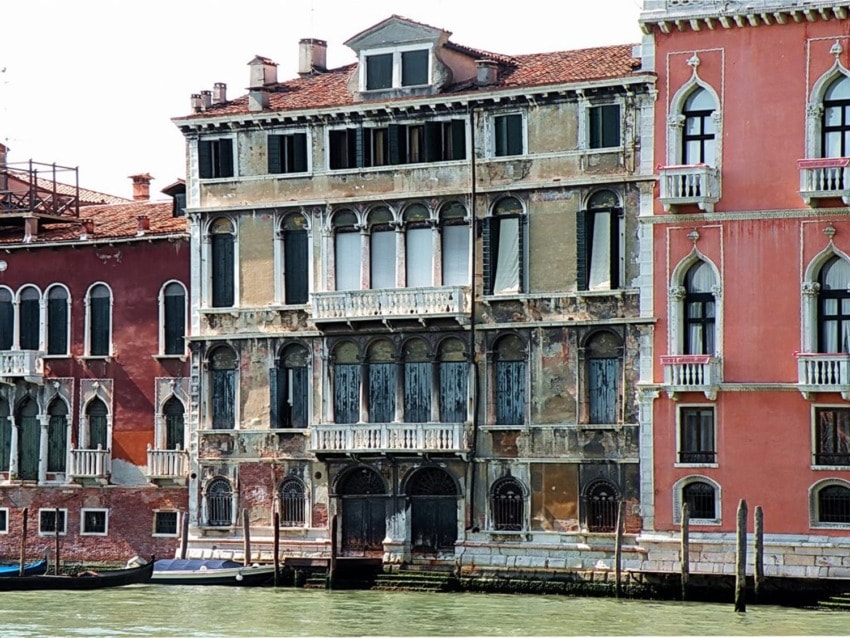 Historic Venetian buildings along a canal with weathered facades and arched windows, reflecting the charm of Venice.