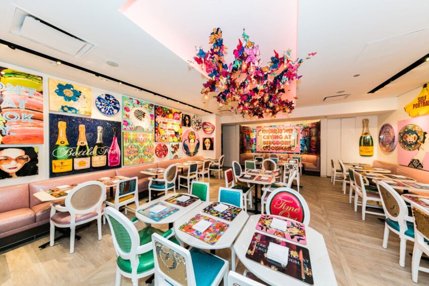 Colorful restaurant interior with vibrant art on walls, tables, and unique overhead decorations.