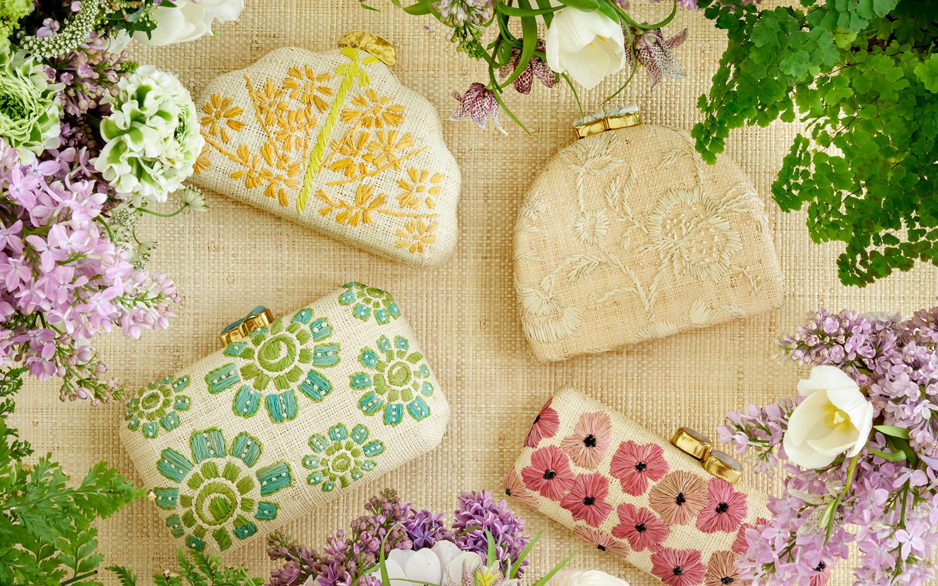 Floral embroidered clutches surrounded by lilacs and white roses on a textured background.
