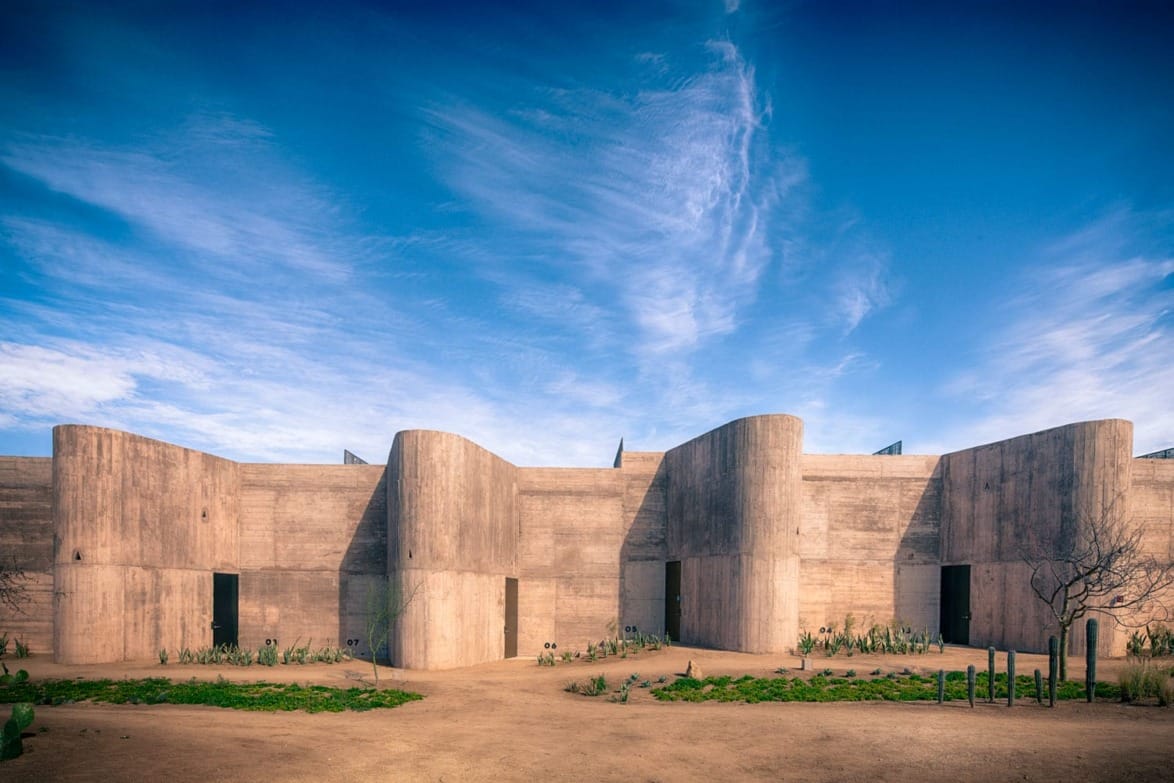Modern architectural building with concrete facade under a vivid blue sky with wispy clouds and minimal landscaping.