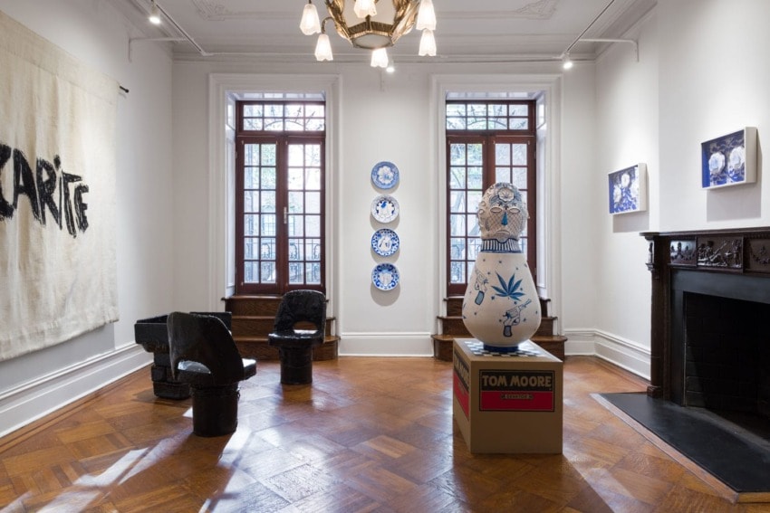 Art gallery interior with decorative plates, sculpture, and modern furniture on a wooden floor.