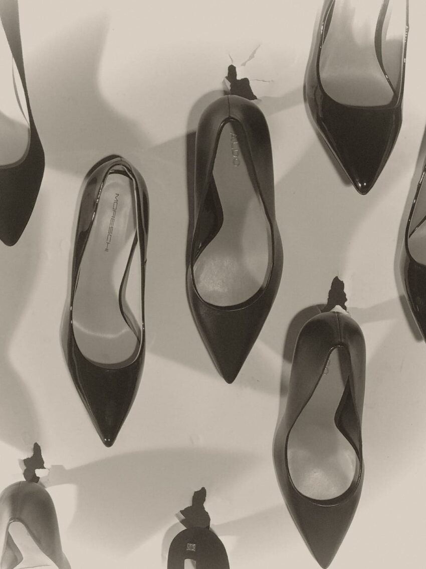 Black high-heeled shoes arranged on a wall-mounted display, showcasing modern fashion style.