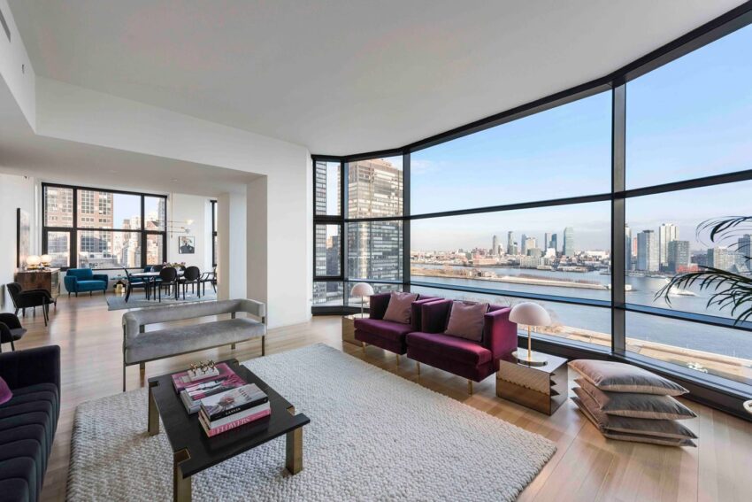 Spacious modern living room with large windows offering a scenic city and river view, featuring stylish furniture and decor.