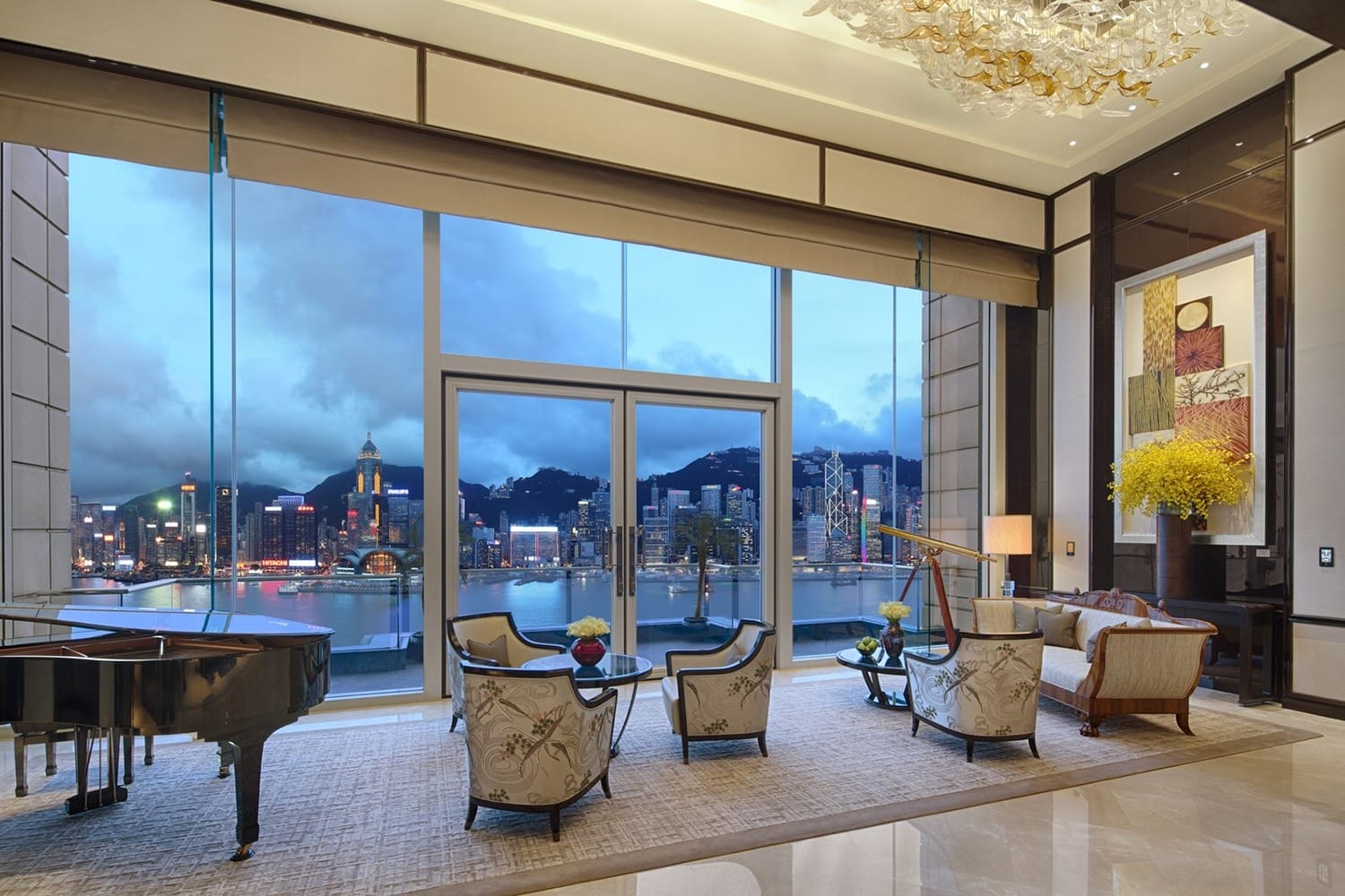 Luxurious living room with elegant furniture, grand piano, large windows, and cityscape view at dusk.