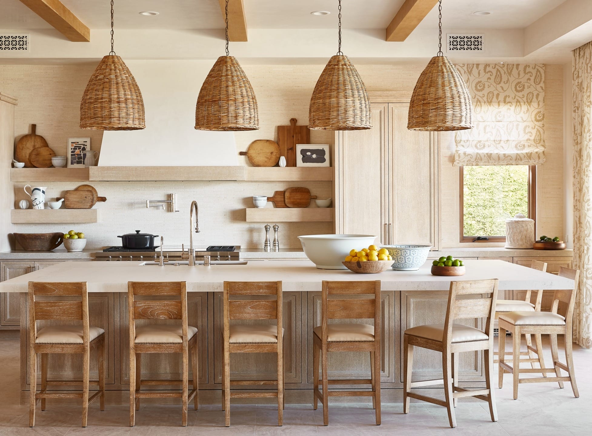 Rustic kitchen with wood island, wicker pendant lights, stools, and decor items on shelves and countertops.