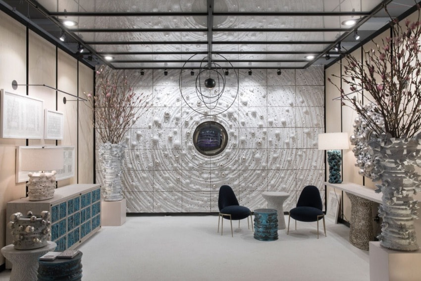 Modern room with textured white walls, two black chairs, abstract decor, and soft lighting.