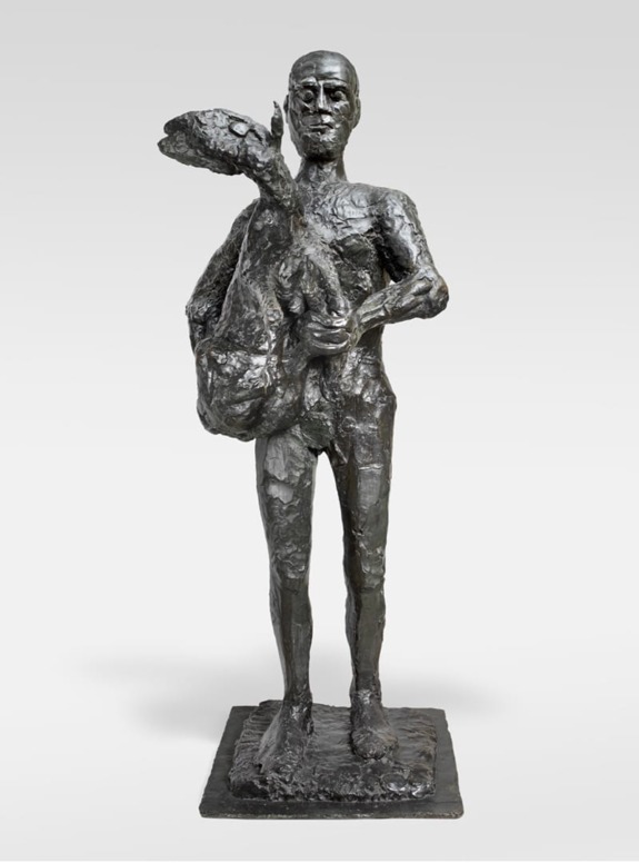 Bronze sculpture of a tall, thin figure holding a lamb, standing on a textured base against a plain background.