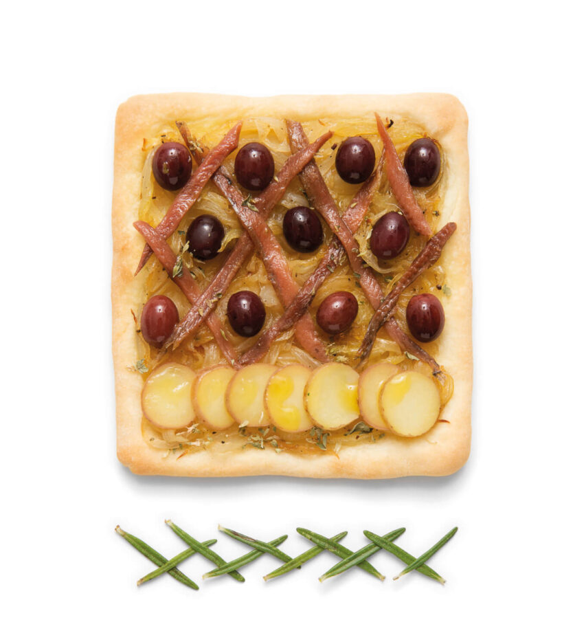 Square pizza with anchovies, grapes, potatoes on top, garnished with chives.