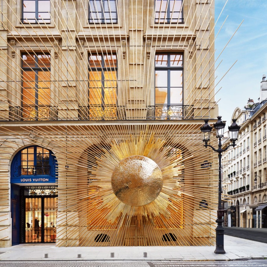 Louis Vuitton store with intricate gold and sunburst facade on a historic street with classic architecture.
