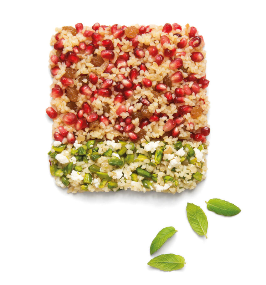 Square-shaped salad with layers of pomegranate seeds, couscous, nuts, and mint leaves garnished with fresh mint leaves.