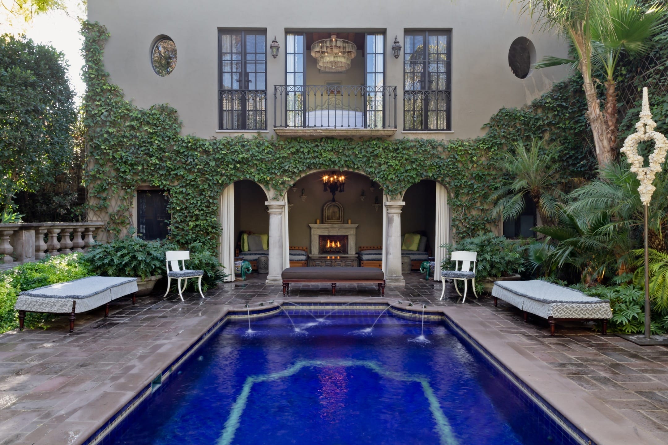 Luxurious outdoor pool area with ivy-covered walls, cozy seating, and elegant architecture for a serene retreat.