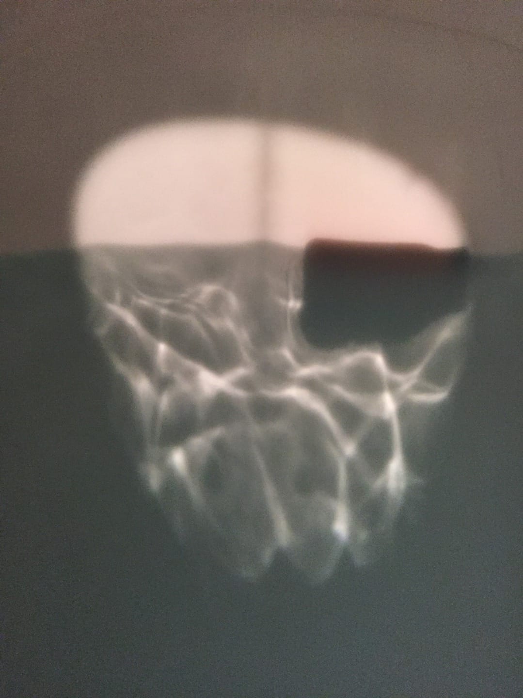 Abstract light reflection resembling a basketball hoop on a wall background.