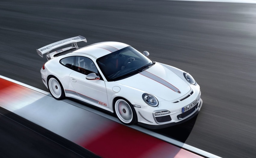 White sports car driving on a racetrack with a large rear spoiler and red accents.