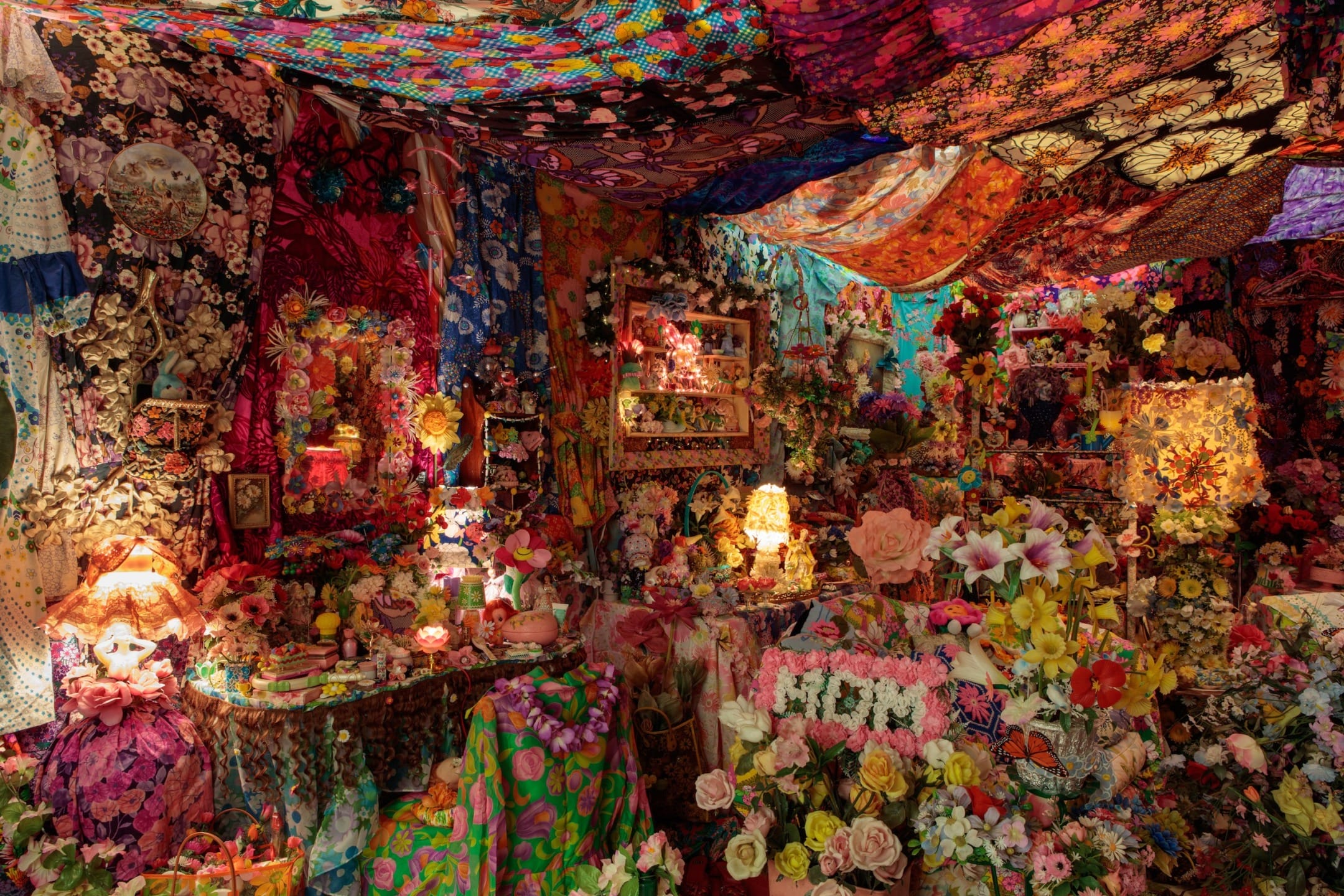 A vibrant room filled with colorful floral patterns and various decorative textiles adorning the walls and ceiling.