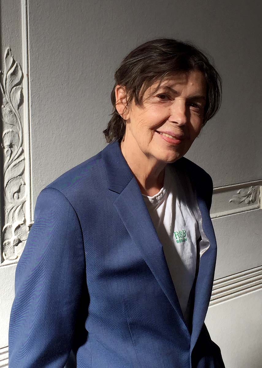 Person in a blue blazer against a textured wall background.