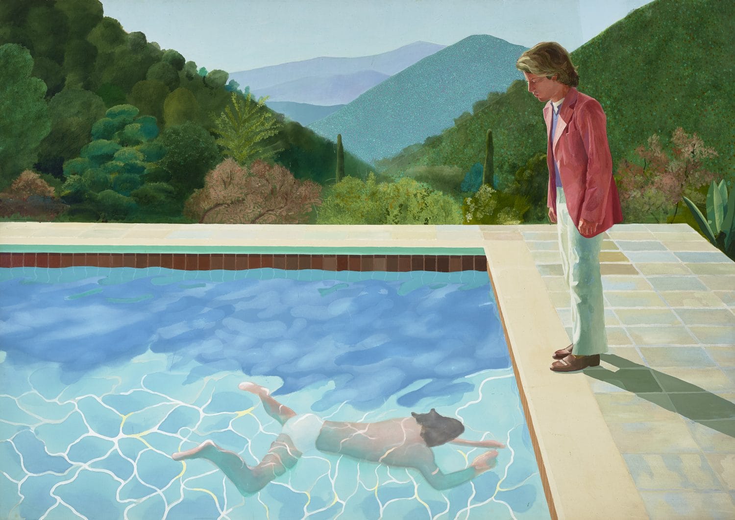A person standing by a pool watching another person swimming underwater, surrounded by lush greenery and hills.