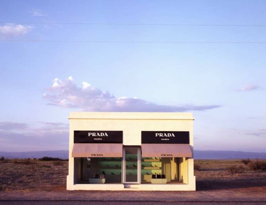 Small Prada store art installation in a vast desert landscape under a clear sky.