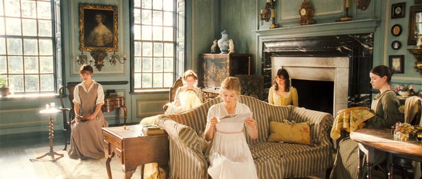 Period room with five women in 19th-century attire, one reading a letter, surrounded by antique furniture and decor.