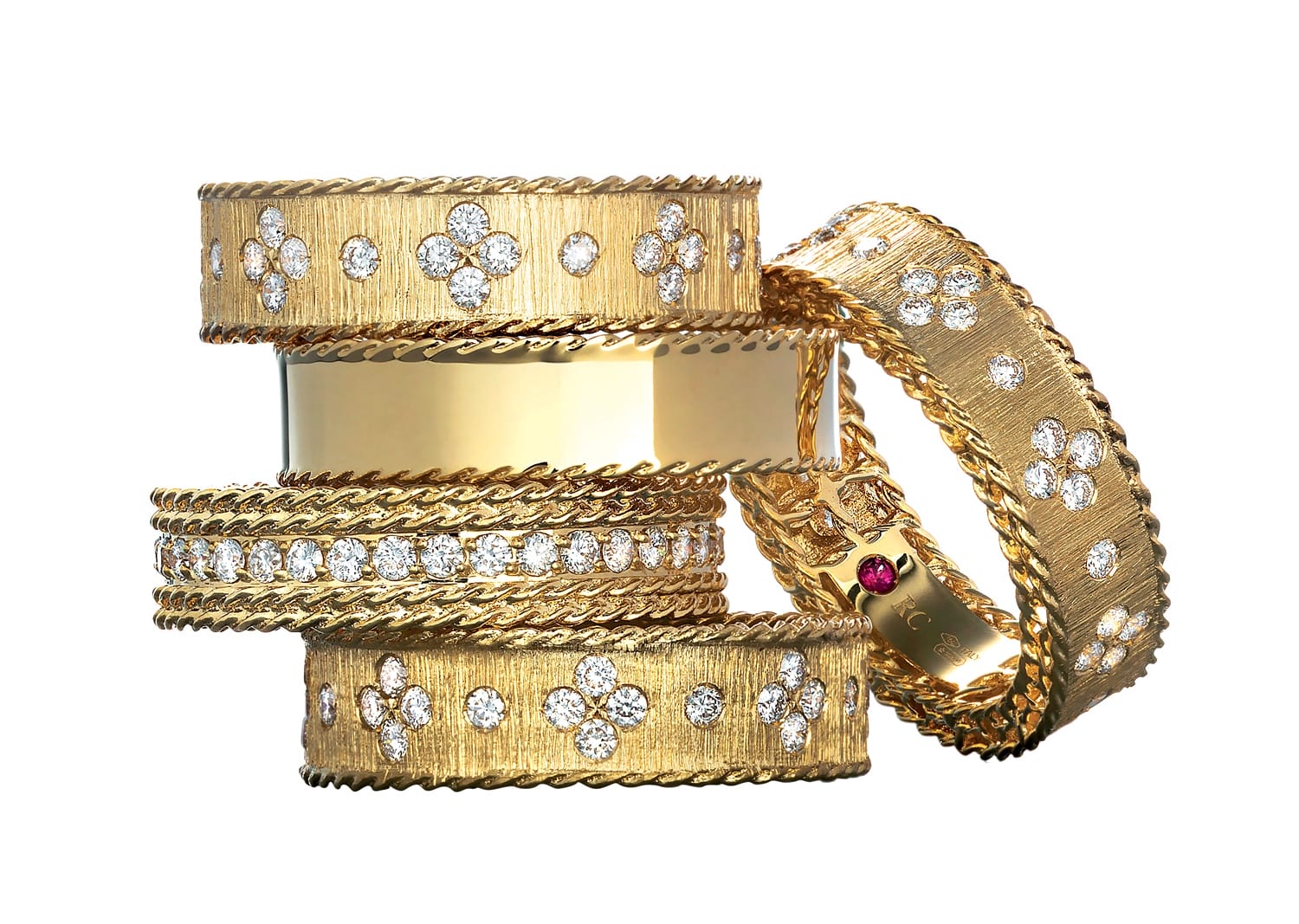 Stack of ornate gold rings with intricate diamond patterns and textured designs.