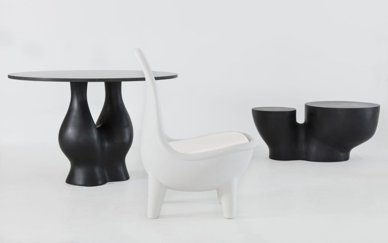 Modern black and white sculptural furniture set featuring a chair, table, and stool in minimalist design on a white background.