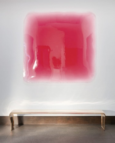 Abstract pink and clear wall sculpture above a minimalist transparent bench in a modern gallery setting.