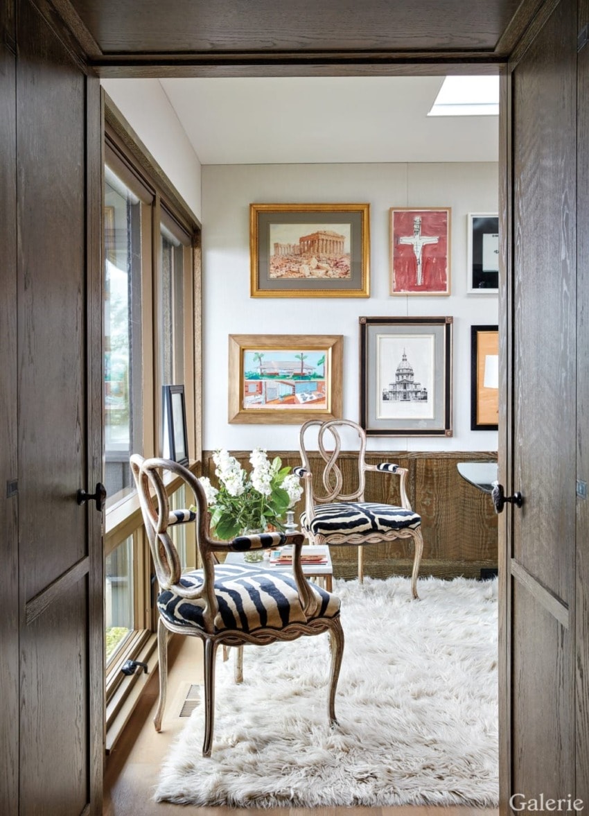 Cozy sitting area with elegant chairs, wall art, and a plush white rug by a window.