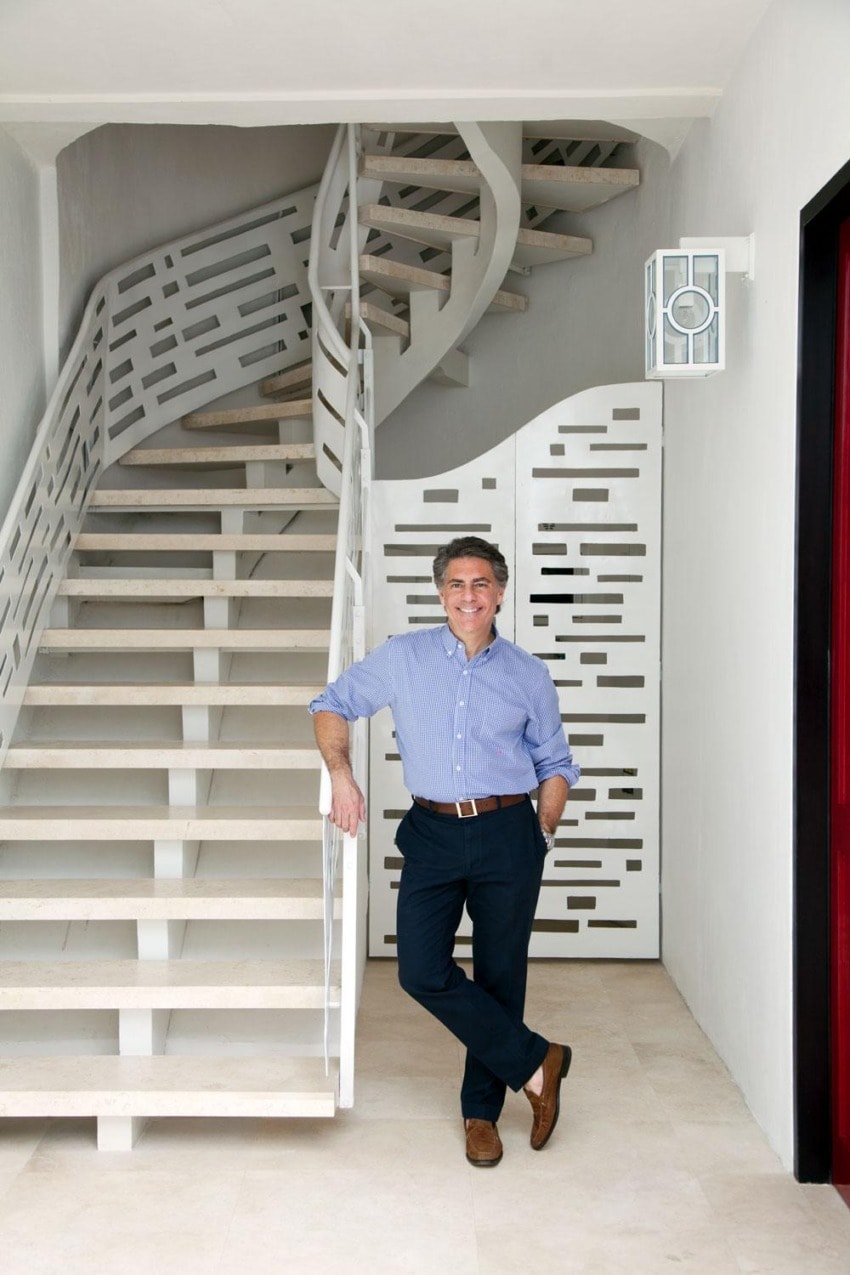 Man in blue shirt standing by a modern spiral staircase with geometric design in a bright interior.