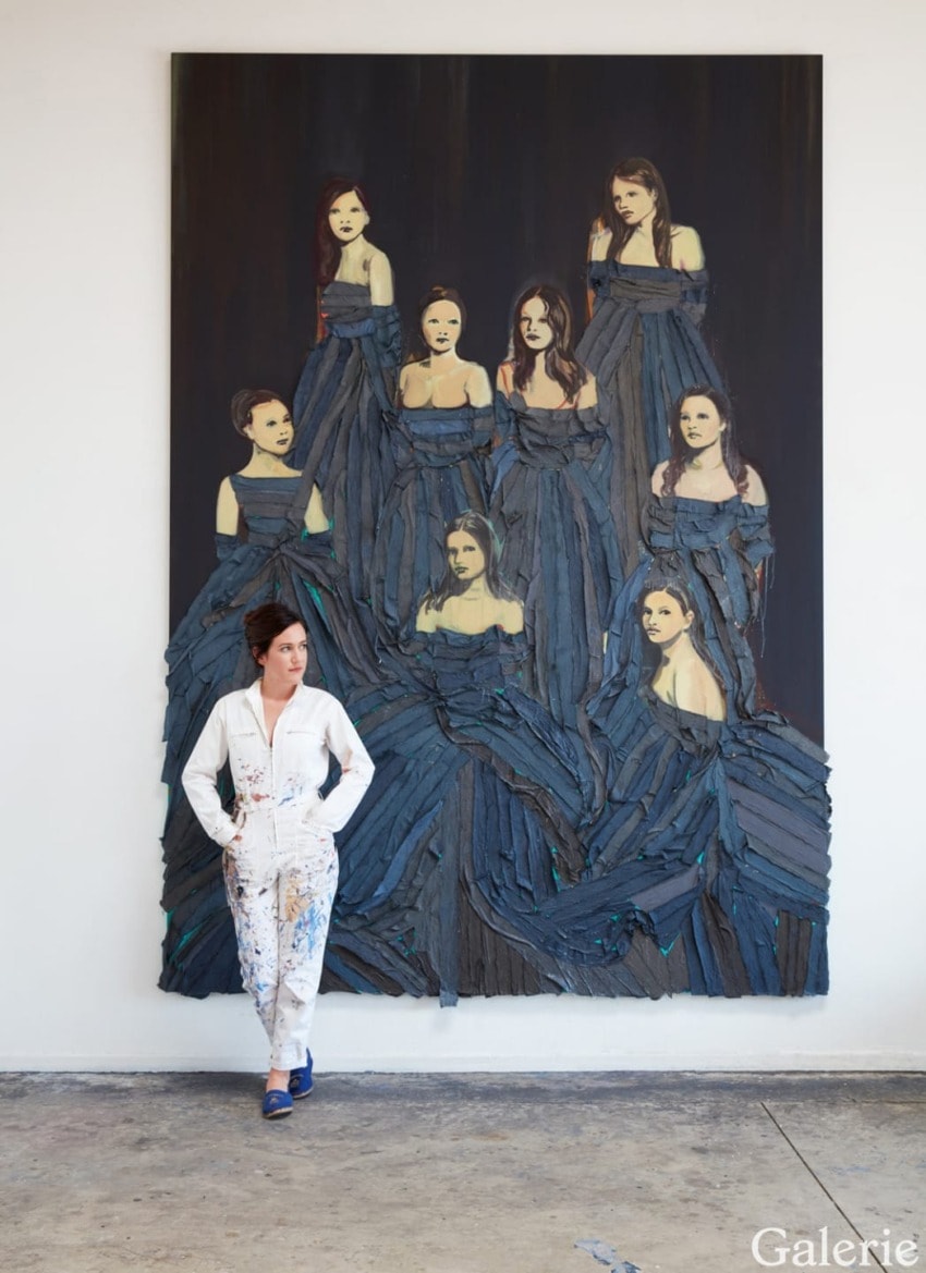 Person standing in front of a large painting depicting seven women in elegant blue dresses.