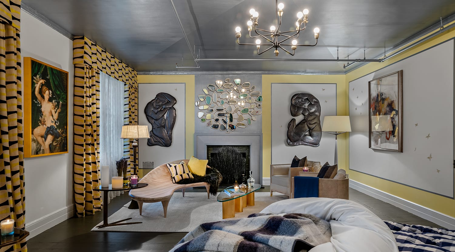 Modern living room with abstract artwork, patterned curtains, a chandelier, and contemporary furniture around a central fireplace.