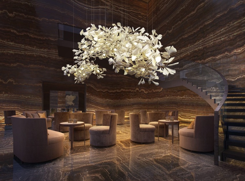 Elegant lounge with modern round chairs and large floral chandelier in a warmly lit, marble-walled room.