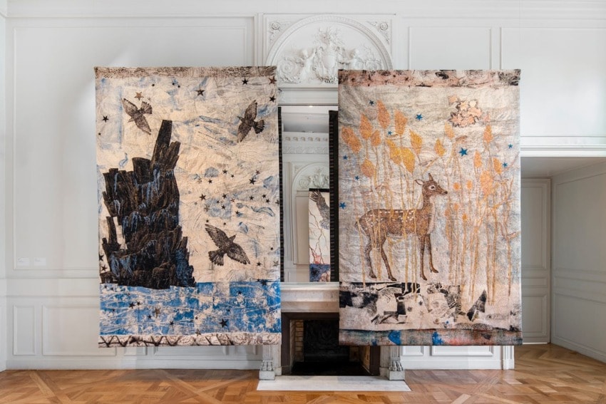 Two large tapestry artworks hanging in an elegant room with white walls and wooden floor, featuring a stag and birds.