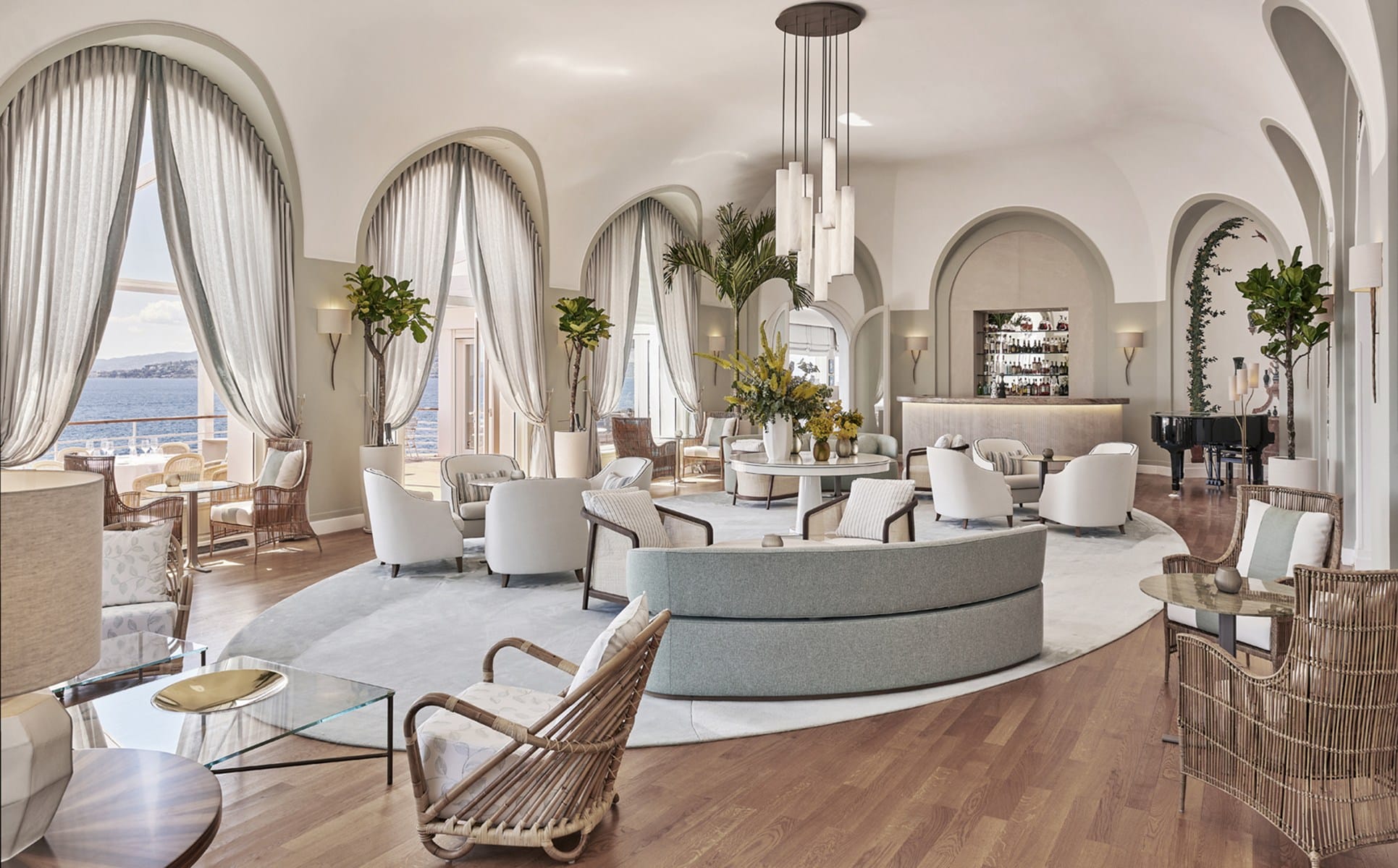 Luxurious hotel lounge with elegant furniture, large windows, ocean view, and modern decor elements including plants and lighting.