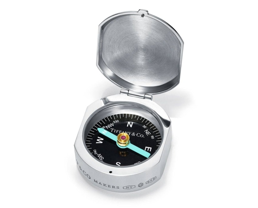 Silver compass with a blue and gold needle, engraved with markings and text, against a white background.