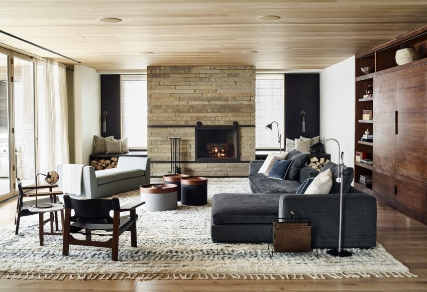 Modern living room with a cozy fireplace, comfortable seating, wooden accents, and a textured rug.