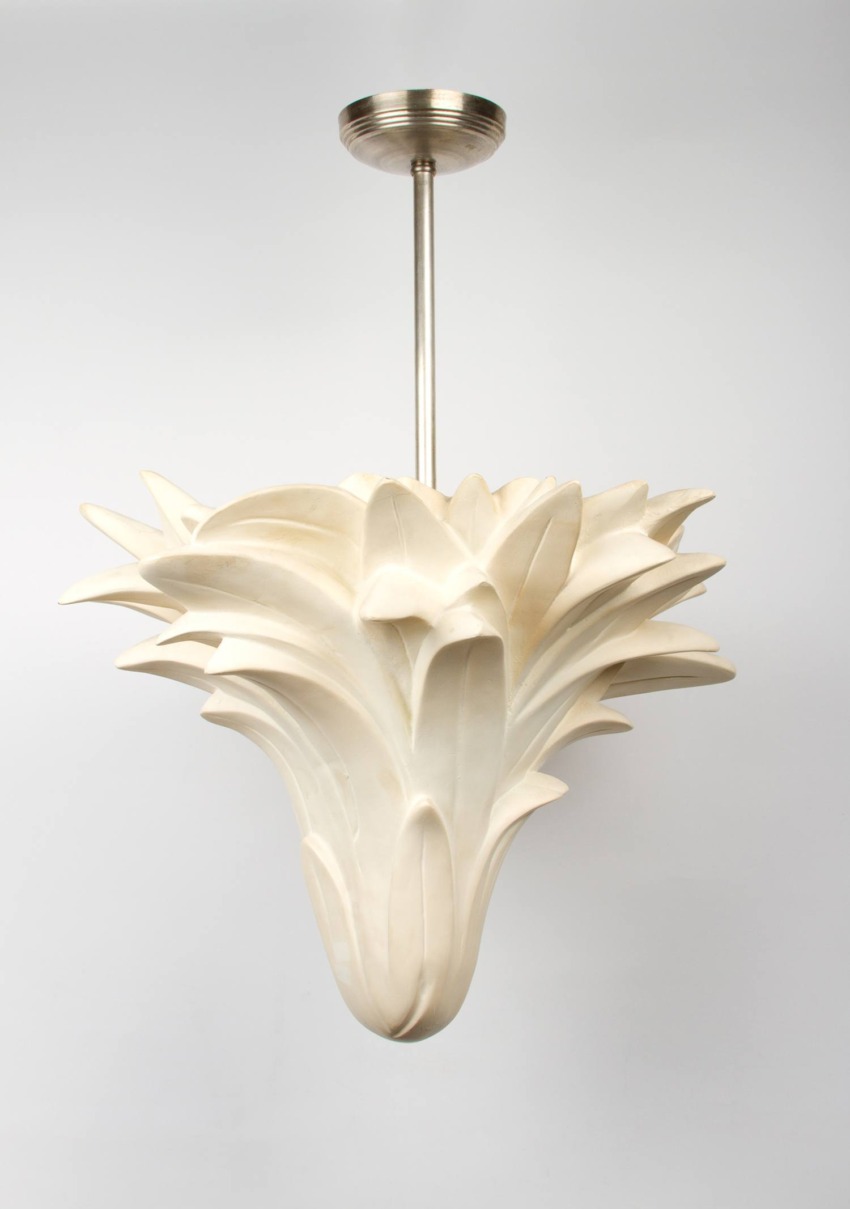 Modern white pendant light with artistic, sculptural design hanging from a metal rod against a plain background.