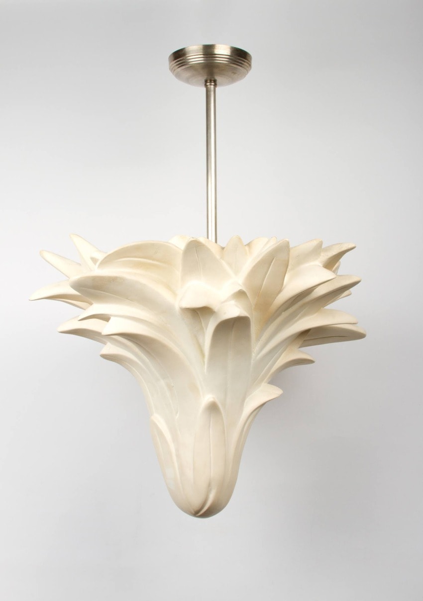 Modern white pendant light with artistic, sculptural design hanging from a metal rod against a plain background.