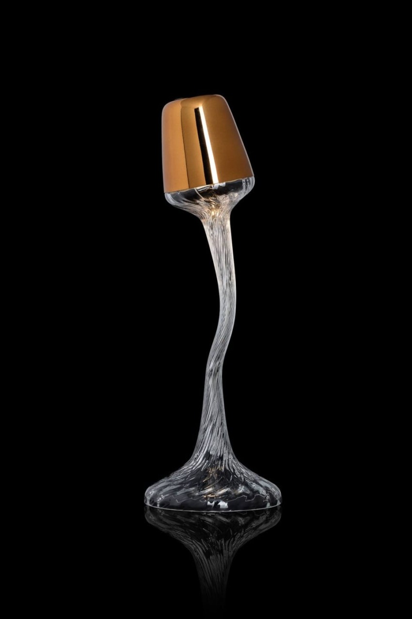 Elegant twisted glass lamp with a gold metallic shade on a black background.