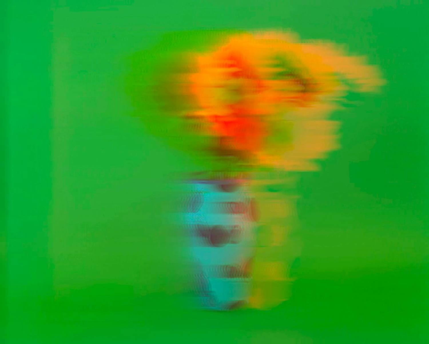 Blurred image of a colorful bouquet of flowers in a blue vase against a green background.