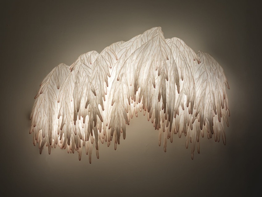 Elegant wall-mounted light fixture with cascading leaves design, softly illuminating the surrounding area.