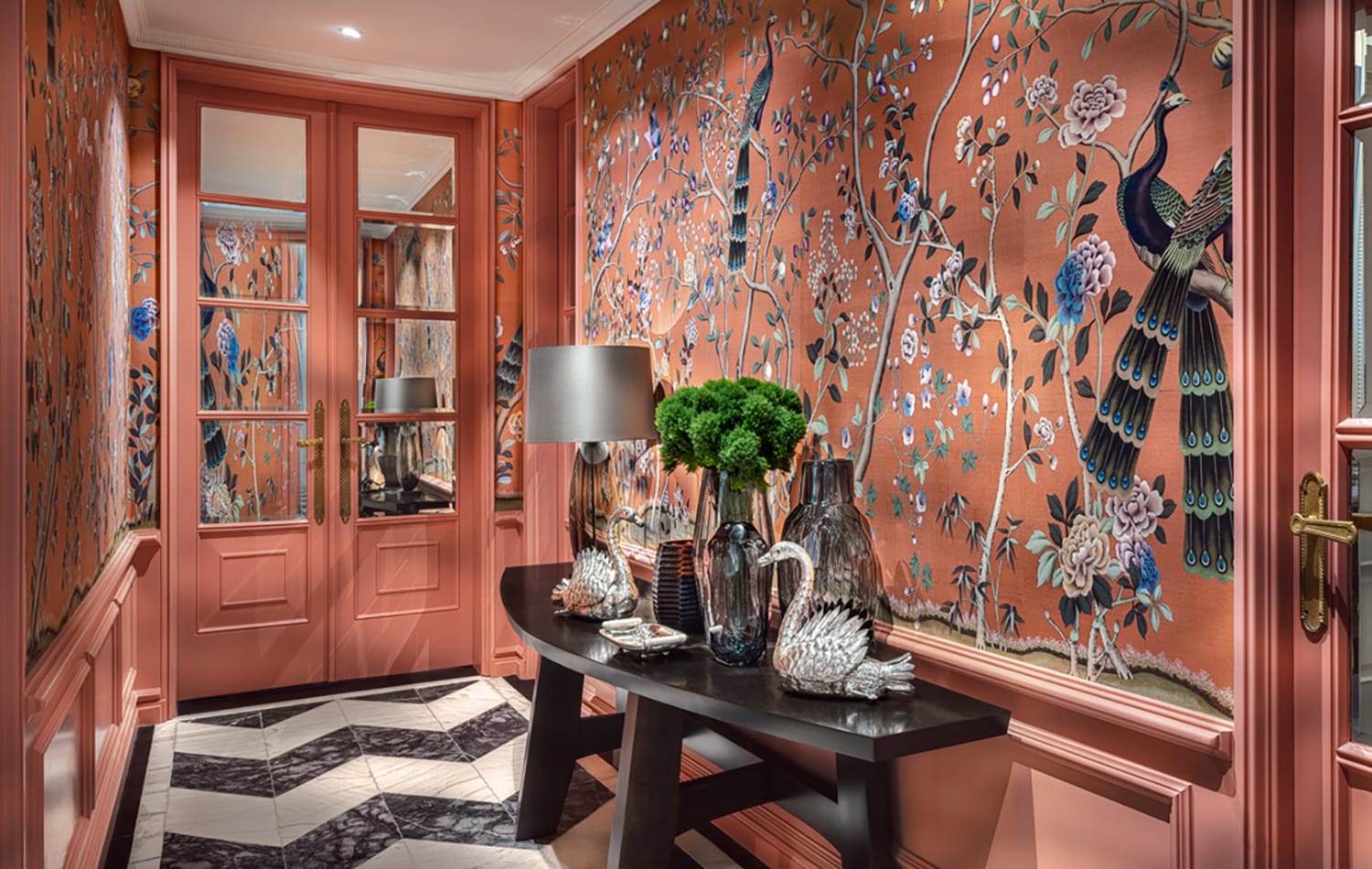 Luxurious hallway with floral and bird patterned wallpaper, decorative vases, green plant, and mirror in elegant interior.