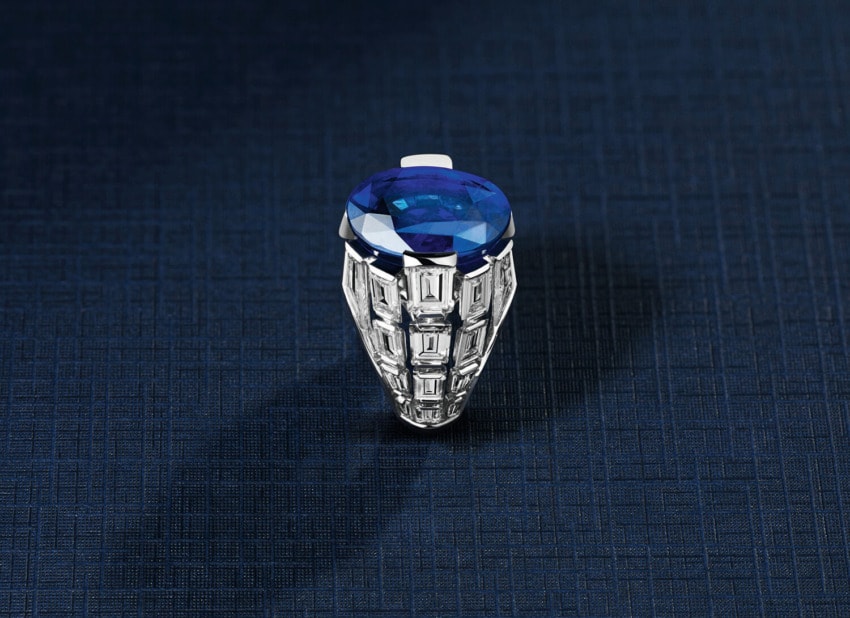 Silver ring with large blue gemstone on dark textured background.