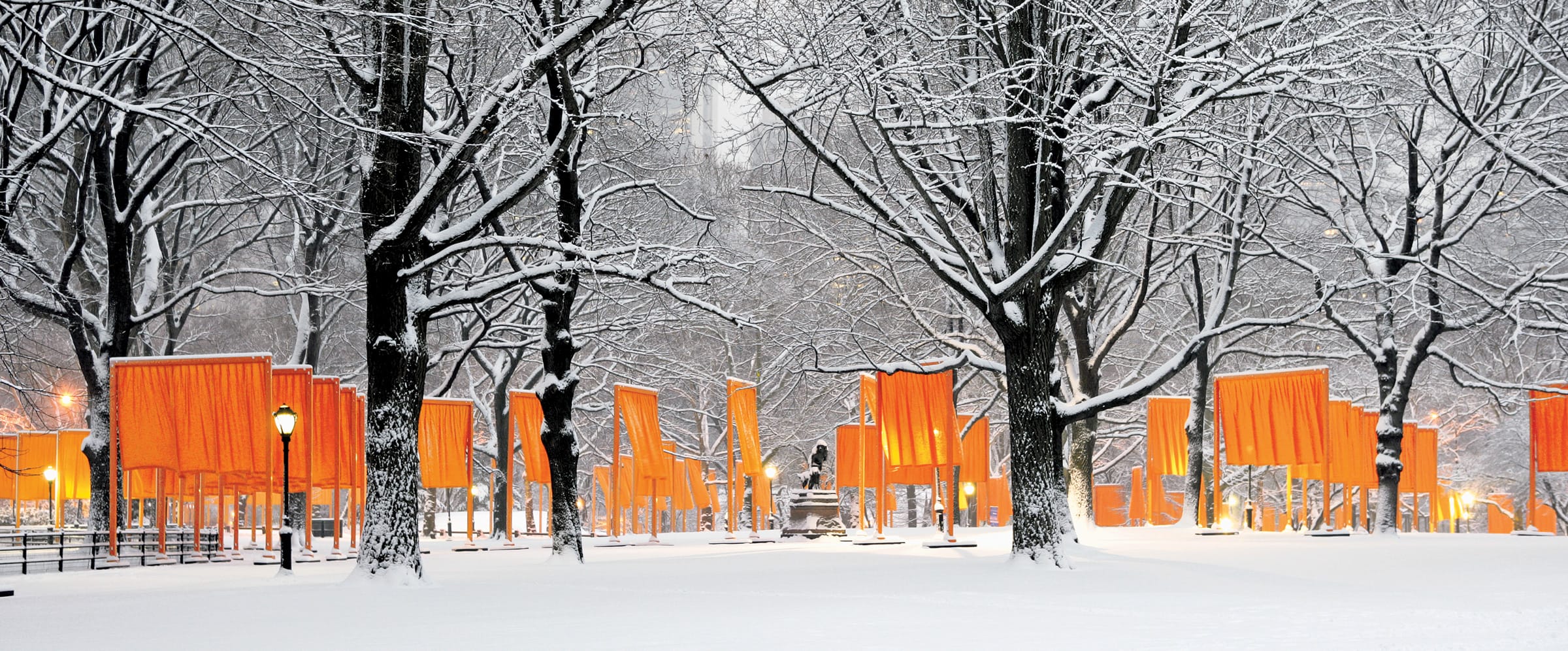 Snowy park scene with orange fabric gates and bare trees in winter.