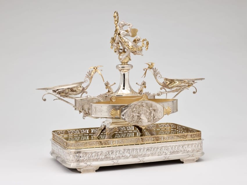 Ornate silver and gold centerpiece with intricate detailing, featuring birds and a floral design.