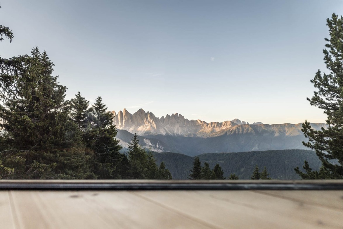 Mountain range and forest view from a wooden deck at sunset with clear sky.