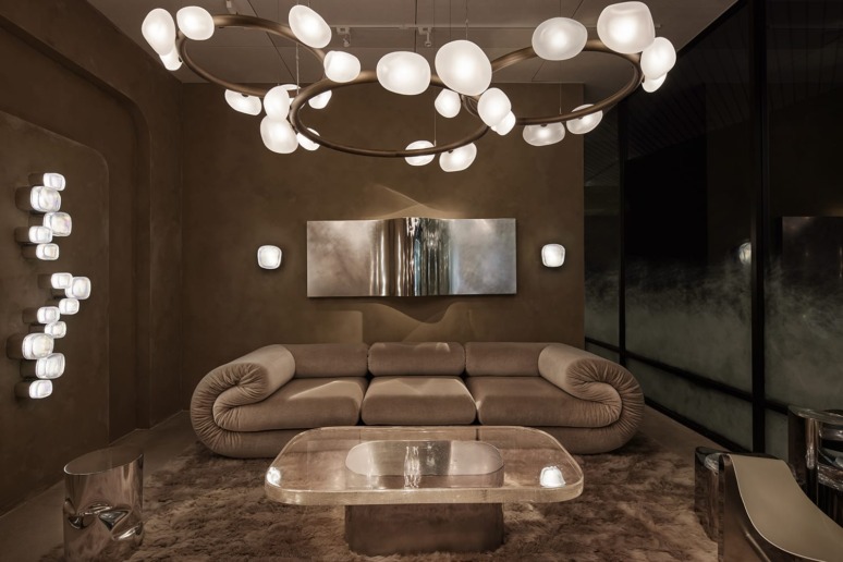 Modern living room with stylish circular chandelier, contemporary sofa, wall art, and elegant glass coffee table.