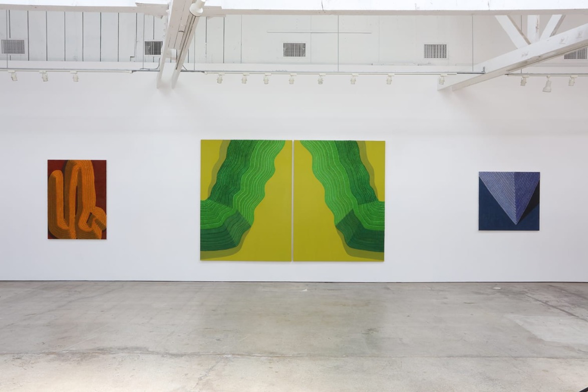 Art gallery with four abstract paintings on white walls, featuring vivid green, yellow, and blue colors.