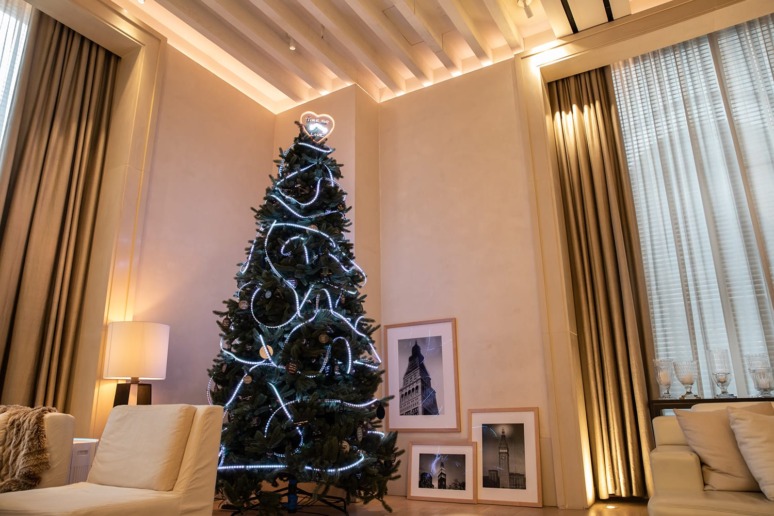 Elegant living room with a decorated Christmas tree, framed pictures on the floor, and comfortable seating.