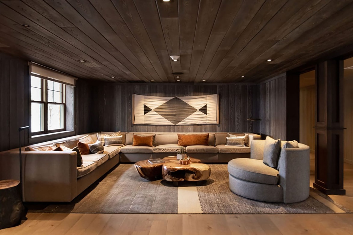 Cozy living room with wooden ceiling, large sectional sofa, and modern wooden coffee table.