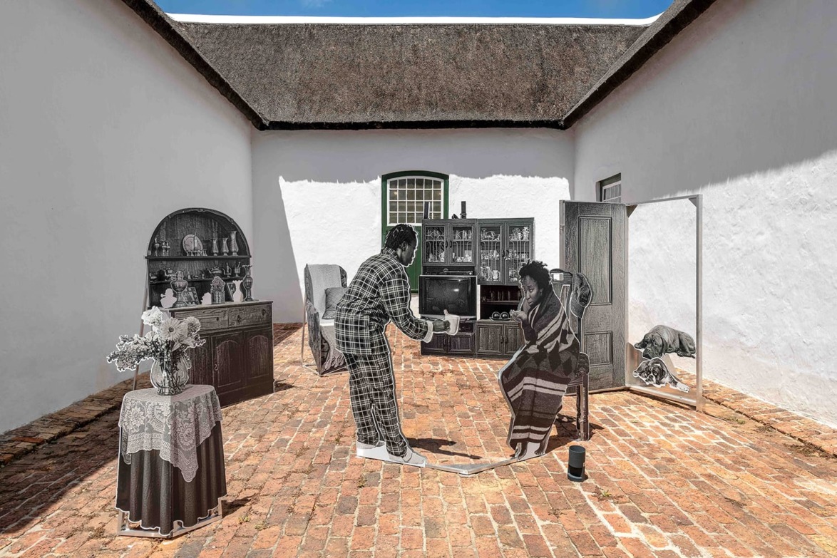 Art installation with life-sized figures in a courtyard, featuring vintage furniture and decorative items under a blue sky.