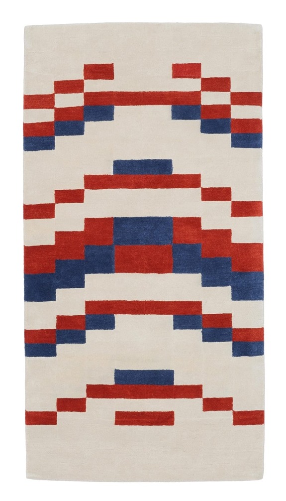 Beige rectangular rug with red and blue geometric patterns forming a symmetrical design.